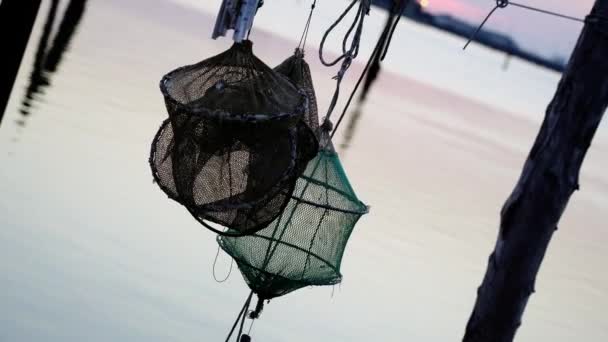 Trampas de pesca negras y verdes cuelgan entre postes de madera — Vídeos de Stock