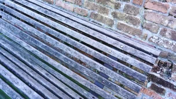 Стара лавка з дерев'яними дошками на металевих опорах цегляною стіною — стокове відео