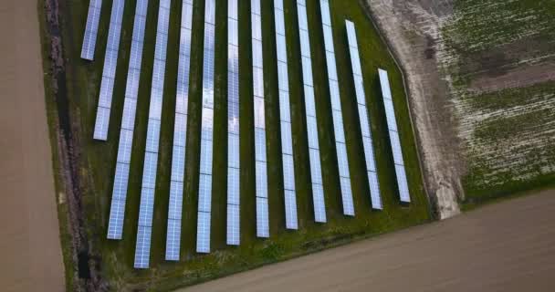 Fotovoltaické panely na zeleném trávníku uprostřed orané půdy — Stock video