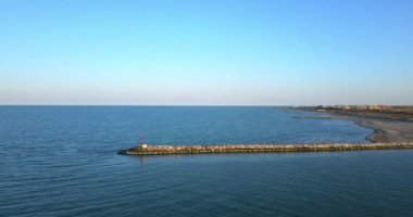 Deniz kıyısında bir baraj ve bir sürü küçük taş ve tuğla barajlar.