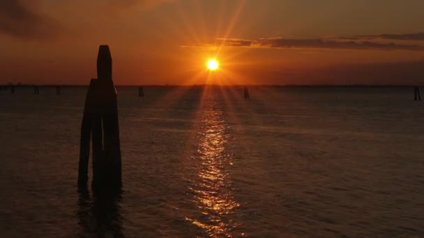 Pilaar silhouetten in donkere zee met kabbelend water bij zonsondergang — Stockvideo