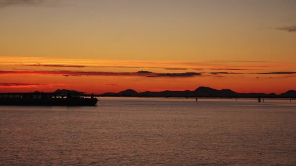 Φορτηγό πλοίο μηχανοκίνητο σκάφος με τους ανθρώπους διασχίζουν σκοτεινή θάλασσα στο ηλιοβασίλεμα — Αρχείο Βίντεο