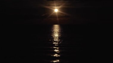 Parlayan ay ışığı uçsuz bucaksız denizde suyu yansıtır.