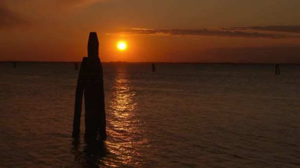 Pillar waterweg marker in donkere Venetiaanse lagune bij zonsondergang — Stockvideo