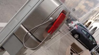 Scooter ve arabalı maskeli kişiye karşı küçük bir telefon kulübesi.