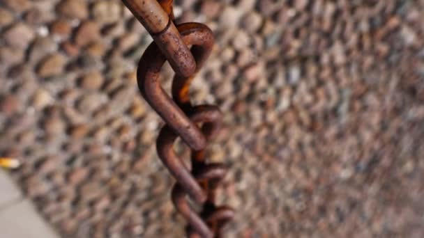 Weathered rusty metal chain over blurry pebble garden path — Stock Video