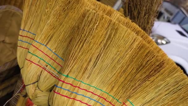 Handmade reed brooms with colored strips in marketplace — Stock Video