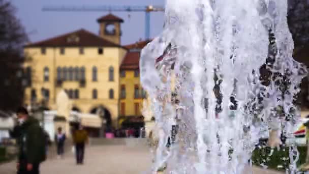 Живописные струи воды из фонтана на фоне размытой городской площади — стоковое видео