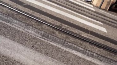 Asfalt yolda paralel tramvay rayları boyunca beyaz yaya geçidi