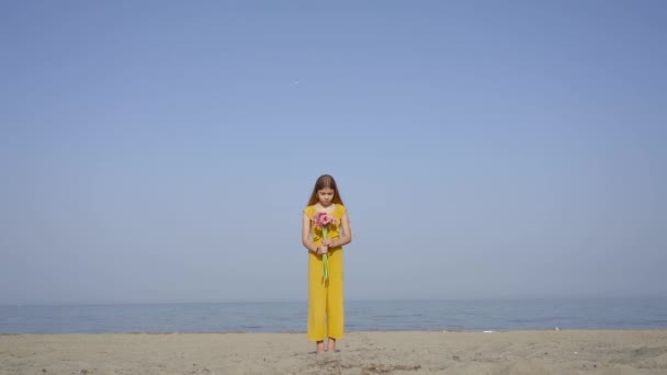 Jovem menina joga flores no ar em câmera lenta na praia — Vídeo de Stock