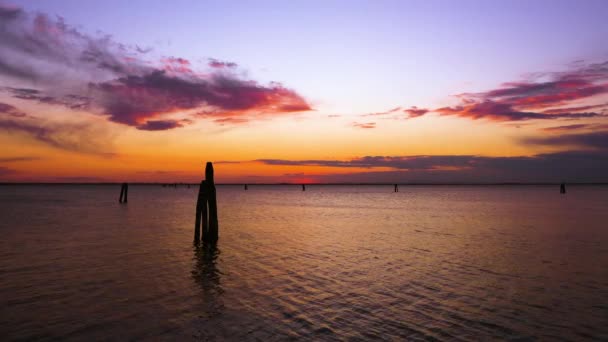 Silhuetas de pilar escuro na lagoa ondulante ao pôr-do-sol — Vídeo de Stock