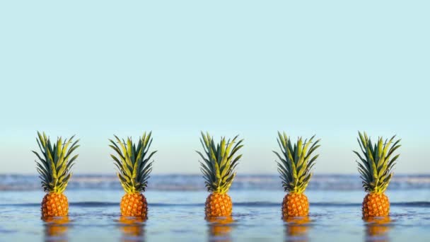 Lezzetli ananaslar sahildeki deniz dalgalarıyla kaplıdır. — Stok video