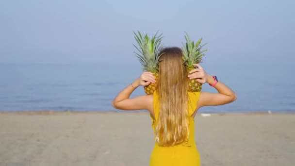 Chica lleva dos piñas en sus hombros en la playa — Vídeos de Stock