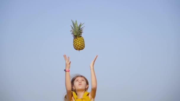 Дівчина кидає ананас у повітря повільним рухом — стокове відео
