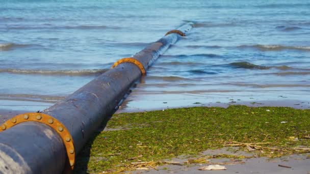 Um grande tubo passa debaixo da água do mar na praia — Vídeo de Stock