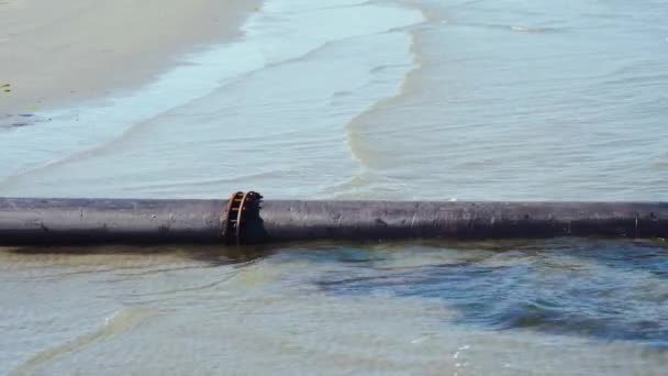 Um tubo junto ao mar na praia e na água — Vídeo de Stock