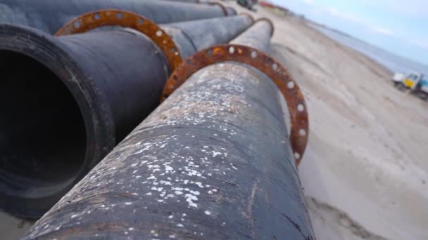 Pipes resting on the sand ready to be used on the construction site — Stock Video