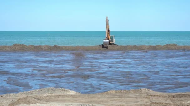 Graafmachine verplaatst zich snel naar de zijkanten naar de bouwplaats aan het strand — Stockvideo