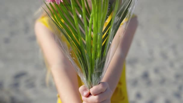 Adolescente sostiene un ramo de flores en la mano y mira hacia adelante con mirada seria — Vídeos de Stock