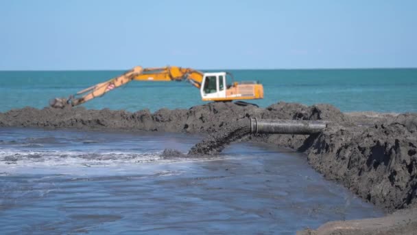Areia molhada é jogada com uma mangueira na praia — Vídeo de Stock