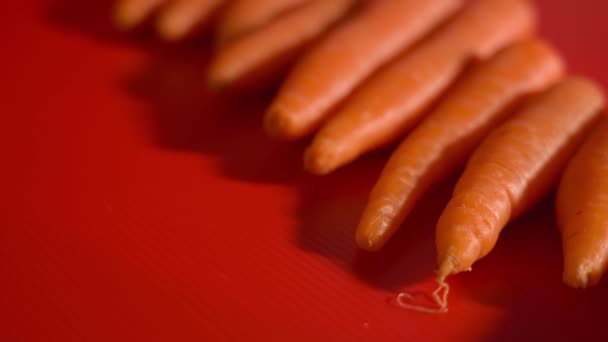 Smaczne pomarańczowe marchewki na czerwonym tle — Wideo stockowe