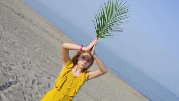 Chica tiene en la mano una hoja verde de flores en el mar — Vídeos de Stock