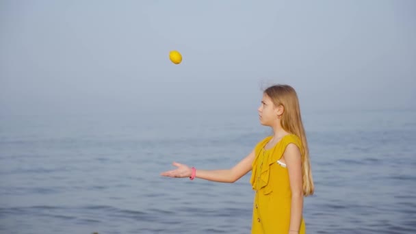 Young girl throws a lemon in front of the sea — Stock Video