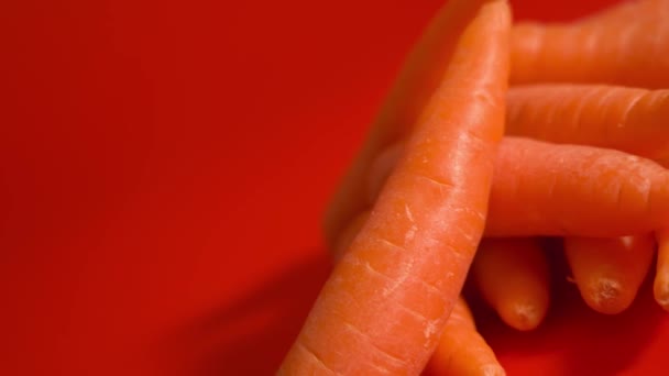 Вкусная оранжевая морковь на красном фоне — стоковое видео