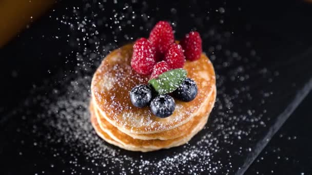 Banketbakkerspoeder valt in slow motion op pannenkoeken met aardbeien — Stockvideo