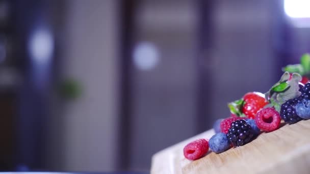 Kleurrijk fruit valt in slow motion van de houten tablet — Stockvideo