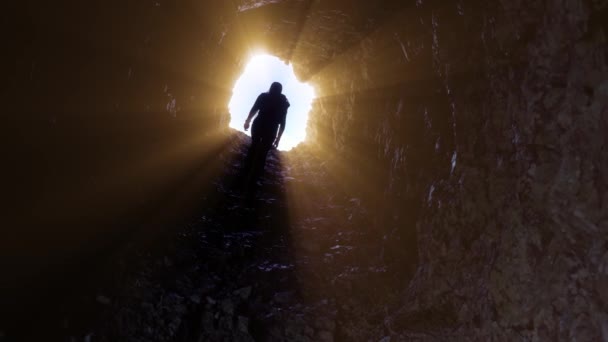 Wanita berjalan di terowongan batu dengan sinar — Stok Video
