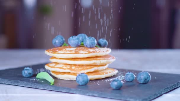 Polvere di pasticceria cade al rallentatore su frittelle con mirtilli — Video Stock