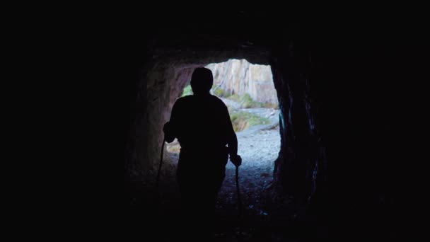 Osoba wchodzi do ciemnej jaskini. — Wideo stockowe