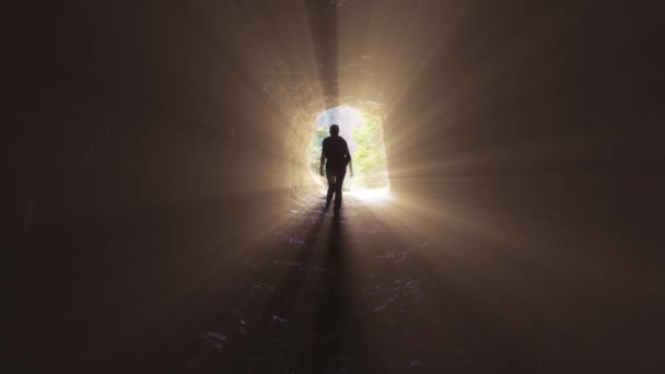 Kobieta spaceruje w kamiennym tunelu z promieniami — Wideo stockowe