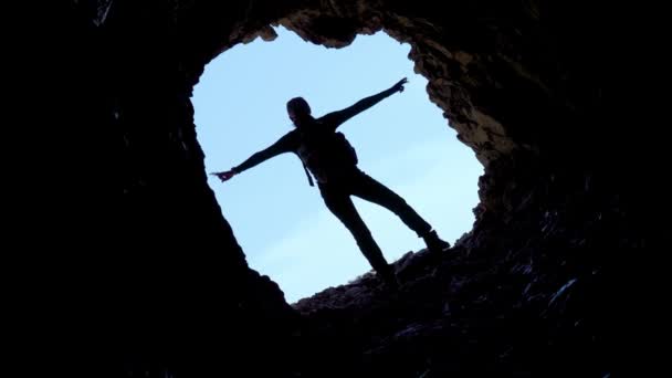 Silhouette of the girl raising arms in the cave — Stock Video