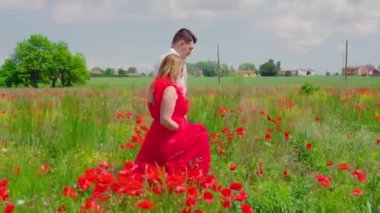 Kız, oğlanla kırmızı haşhaş tarlasında yürüyor.