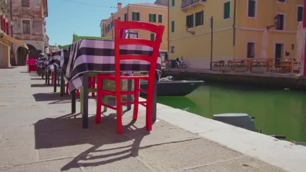 Mesas en el restaurante a lo largo de las orillas del canal de agua Chioggia — Vídeos de Stock