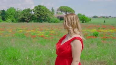 Zarif bir kadın kırmızı haşhaş tarlasının önüne geçiyor.