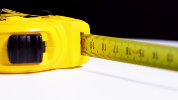 Fita métrica amarela gira sobre mesa branca — Vídeo de Stock