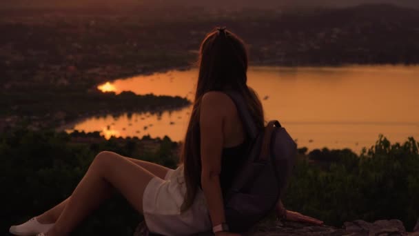 Menina olha para o pôr do sol sobre as montanhas — Vídeo de Stock