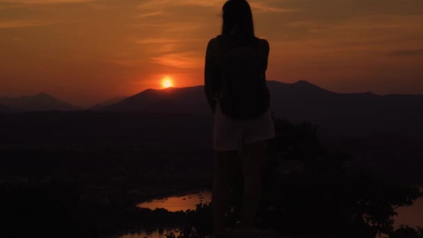 Silhouette des Mädchens von hinten beim Betrachten des Sonnenuntergangs in den Bergen — Stockvideo