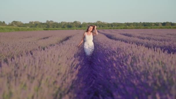 Meisje in de witte jurk loopt tussen lavendelplanten — Stockvideo