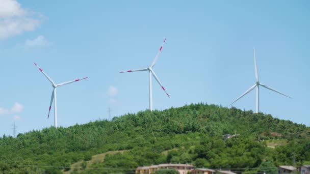 Tres aerogeneradores giran sobre colinas verdes — Vídeos de Stock