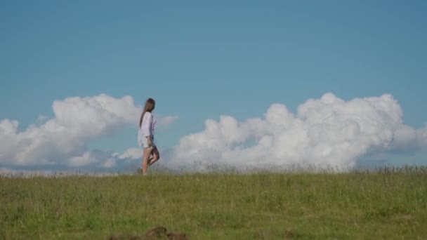 Ragazza cammina sull'erba verde con cielo blu sullo sfondo — Video Stock