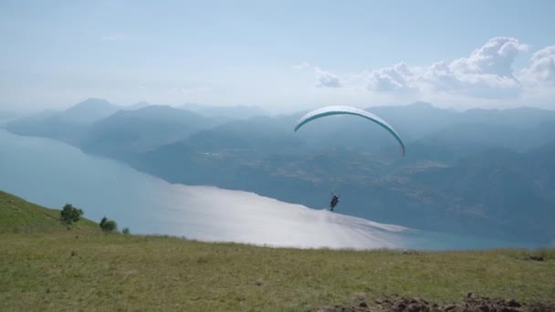 De mens vliegt met een paraglider over het Gardameer — Stockvideo