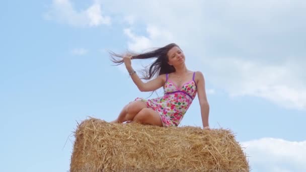 Mulher sentada na bola de feno no fundo do céu azul com nuvens brancas — Vídeo de Stock