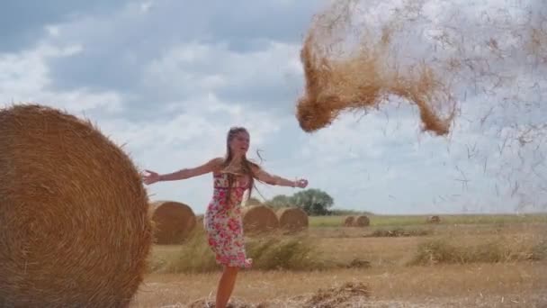 Glückliches Mädchen wirft Heu in die Luft auf dem Feld — Stockvideo