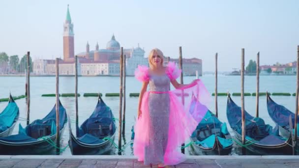 Flicka klädd i rosa i Venedig framför gondolerna på vattnet — Stockvideo