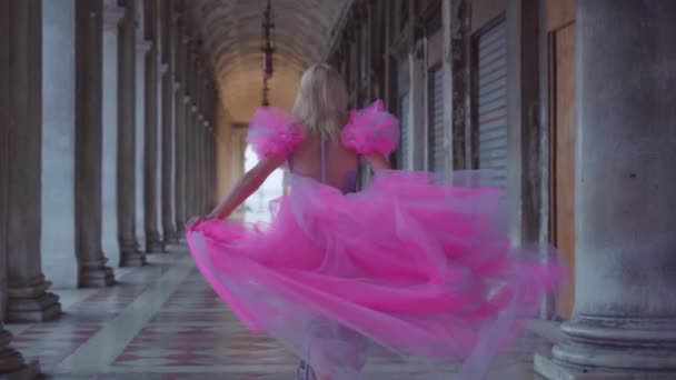 Flicka med rosa klänning körs i slow motion under venetianska arkader — Stockvideo