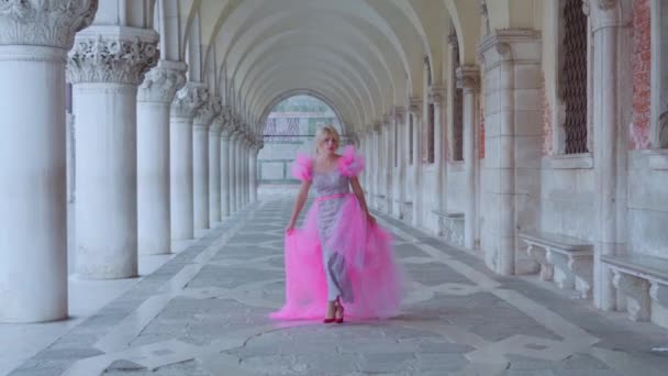 Menina com vestido rosa caminha sob as arcadas de Veneza — Vídeo de Stock